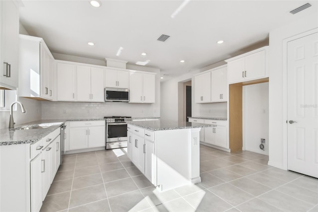 kitchen with sink, white cabinetry, a center island, stainless steel appliances, and light stone countertops