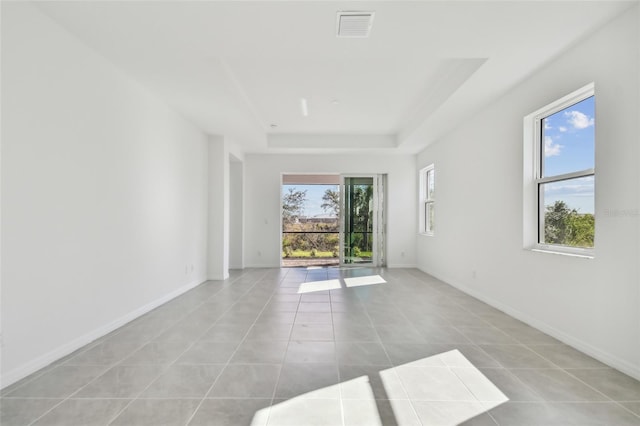 empty room with a tray ceiling and light tile patterned floors