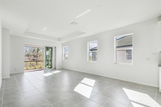 unfurnished room with light tile patterned floors and a raised ceiling