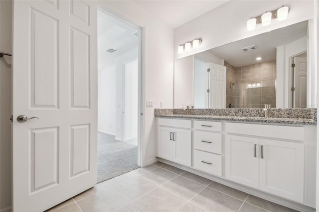 bathroom featuring a tile shower, vanity, and tile patterned floors