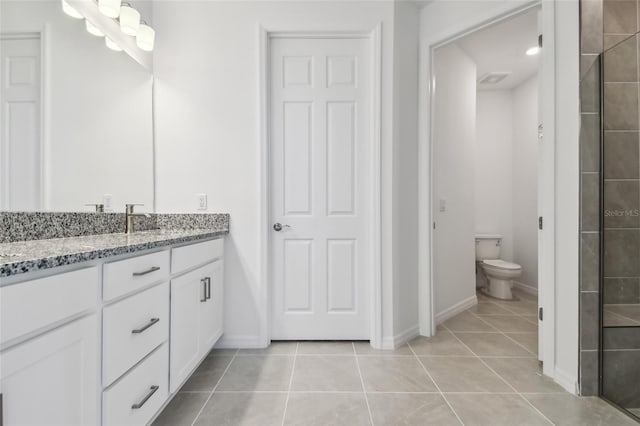 bathroom with walk in shower, vanity, toilet, and tile patterned flooring