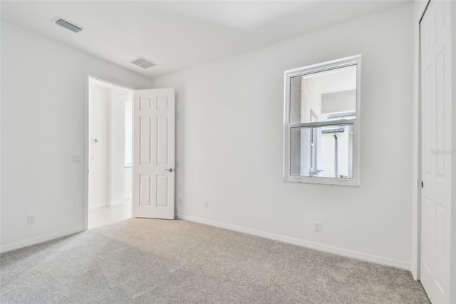 unfurnished bedroom featuring light carpet and a closet