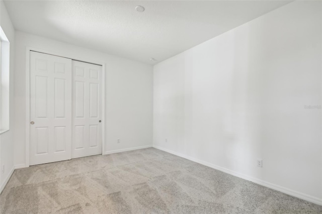 unfurnished bedroom with light colored carpet and a closet