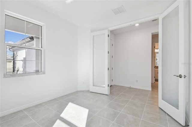 tiled empty room featuring french doors