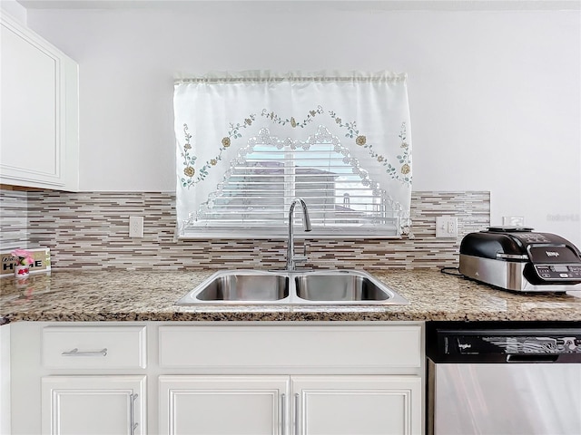 kitchen featuring tasteful backsplash, white cabinetry, dishwasher, sink, and light stone counters