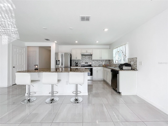 kitchen with a kitchen island, a breakfast bar, sink, dark stone counters, and stainless steel appliances