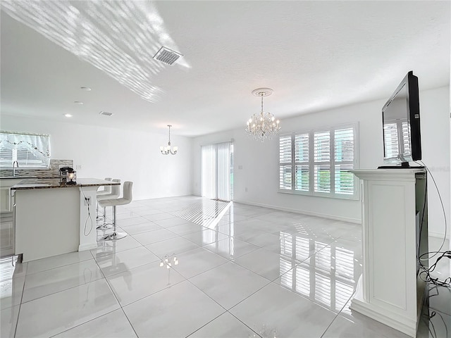 interior space with an inviting chandelier, a textured ceiling, and light tile patterned flooring