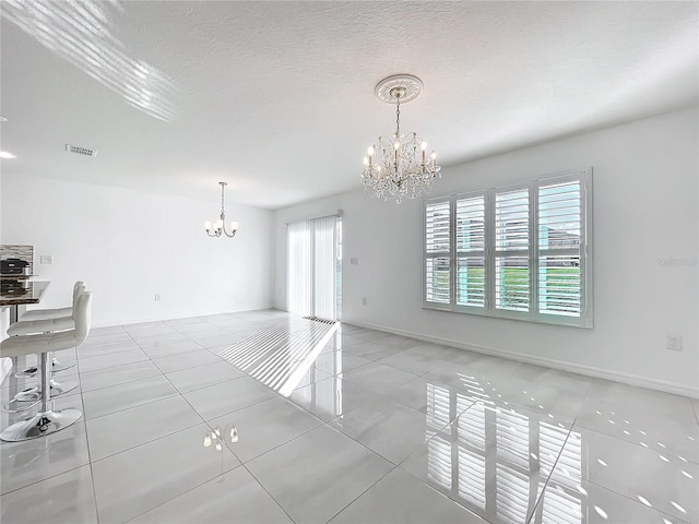 interior space with a notable chandelier, a textured ceiling, and light tile patterned flooring