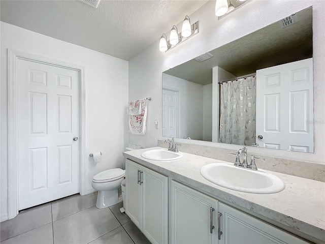 bathroom with vanity, toilet, tile patterned flooring, and a textured ceiling