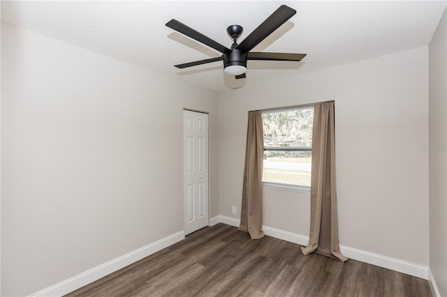 empty room with ceiling fan, wood finished floors, and baseboards