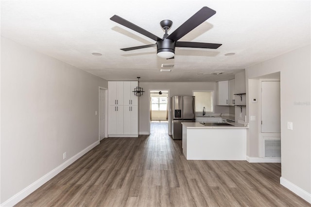 kitchen featuring stainless steel fridge, visible vents, wood finished floors, light countertops, and a sink