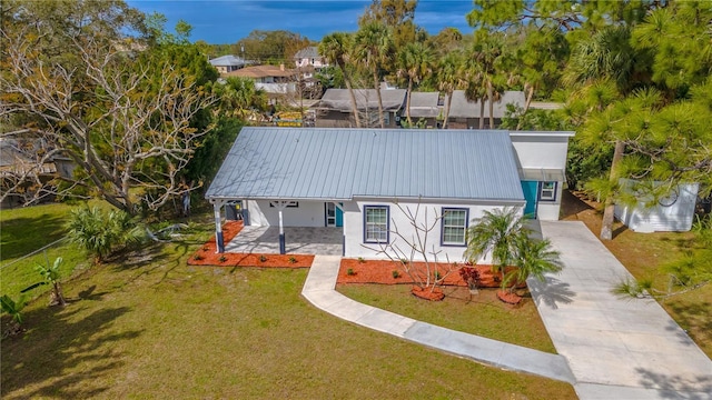 view of front of house featuring metal roof, a front lawn, concrete driveway, and stucco siding