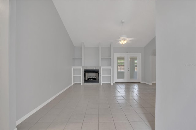 unfurnished living room with built in shelves, a fireplace, lofted ceiling, a ceiling fan, and baseboards