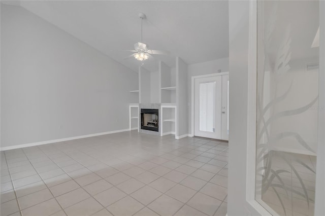 unfurnished living room with light tile patterned floors, built in features, lofted ceiling, ceiling fan, and a fireplace