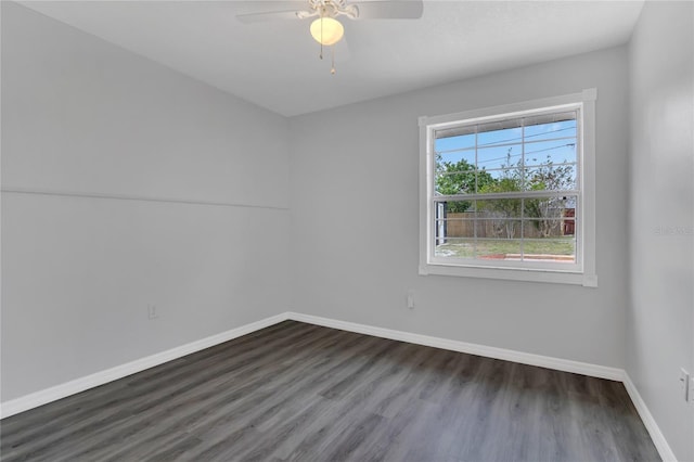 spare room featuring a ceiling fan, dark wood finished floors, and baseboards