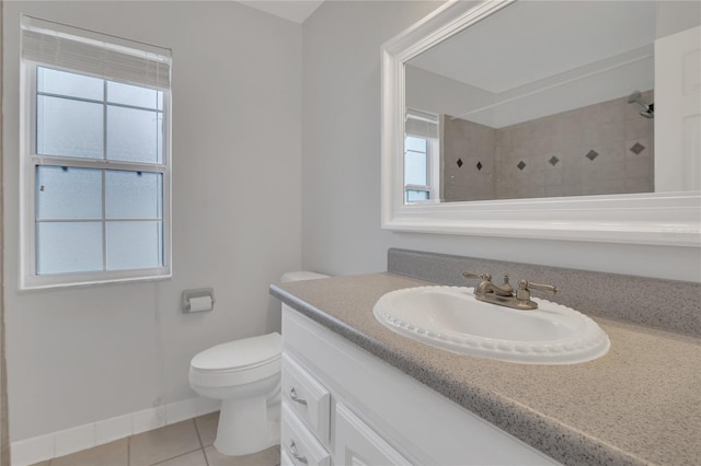 bathroom with toilet, vanity, baseboards, tiled shower, and tile patterned floors