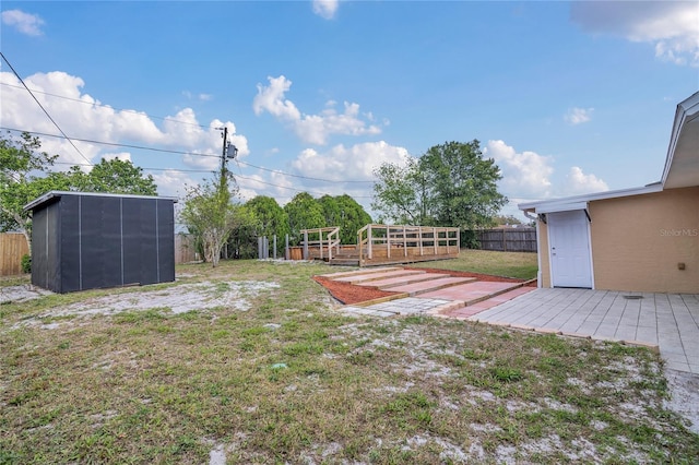 view of yard with an outbuilding, a fenced backyard, a wooden deck, and a storage unit