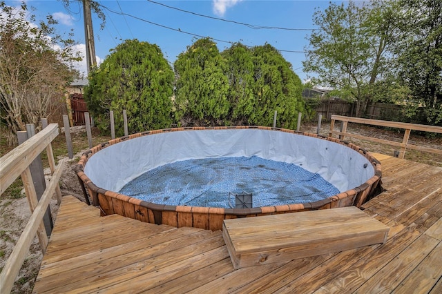 view of swimming pool with fence, a hot tub, and a wooden deck