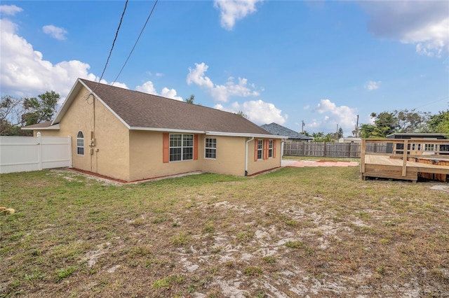 back of house featuring a deck, a yard, a fenced backyard, and stucco siding