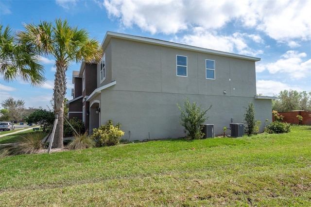 view of side of home featuring central air condition unit, a lawn, and stucco siding