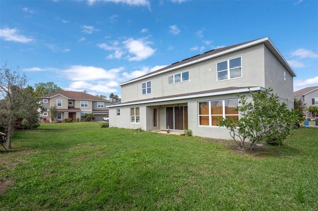 rear view of house with stucco siding and a yard