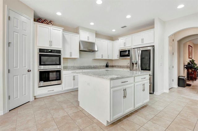 kitchen with appliances with stainless steel finishes, arched walkways, white cabinets, and under cabinet range hood