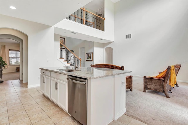 kitchen featuring arched walkways, stainless steel dishwasher, and light colored carpet