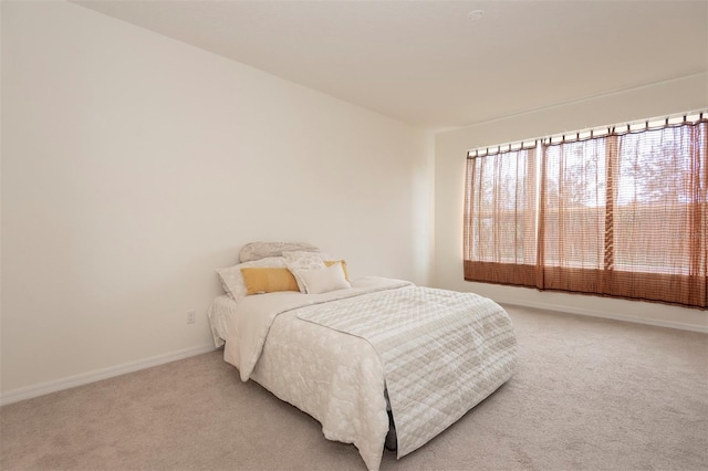 bedroom with light carpet and baseboards