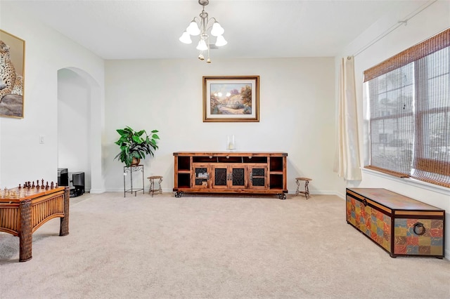 sitting room featuring arched walkways, baseboards, carpet flooring, and a chandelier