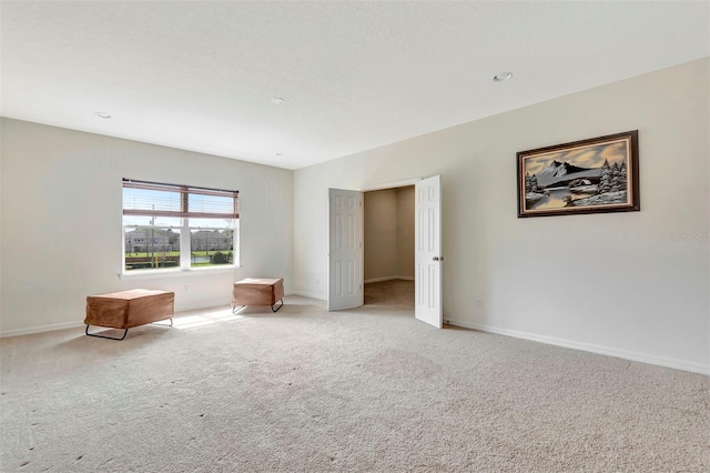 unfurnished room featuring light colored carpet and baseboards