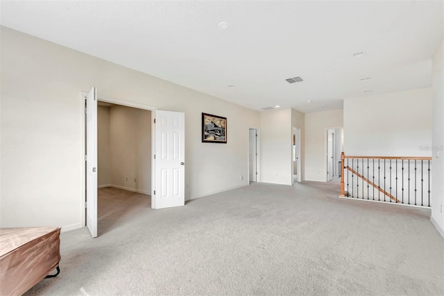 unfurnished room with visible vents, light carpet, and baseboards