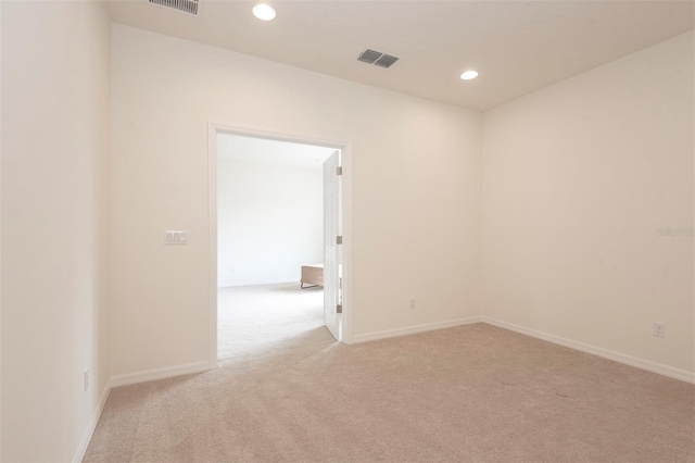 unfurnished room featuring light colored carpet, visible vents, baseboards, and recessed lighting