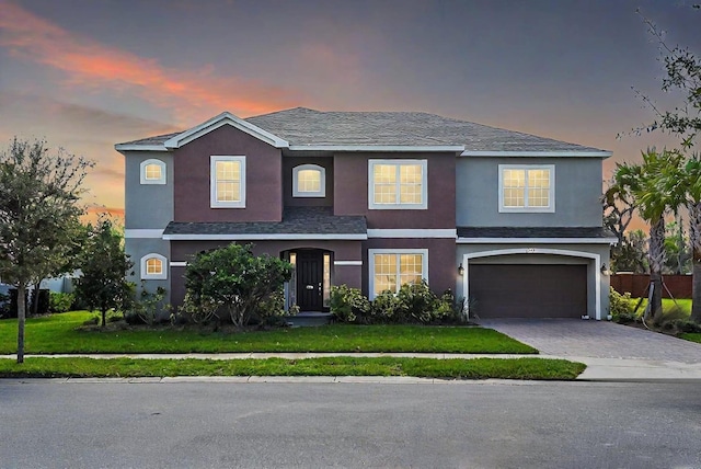 view of front of house featuring a garage, a front lawn, decorative driveway, and stucco siding