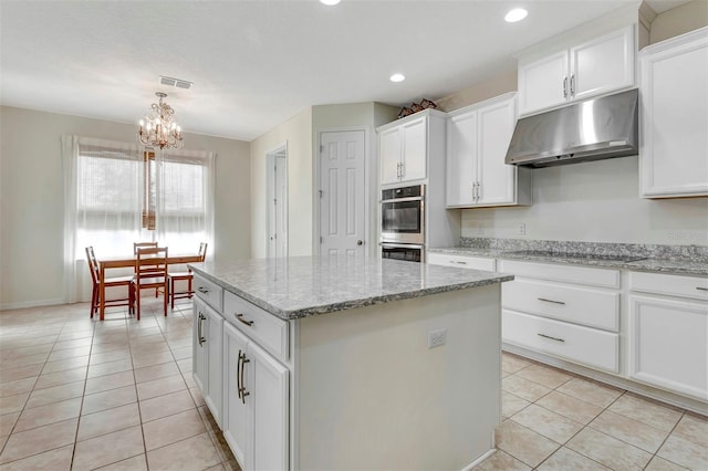 kitchen with under cabinet range hood, light tile patterned floors, visible vents, and black electric cooktop