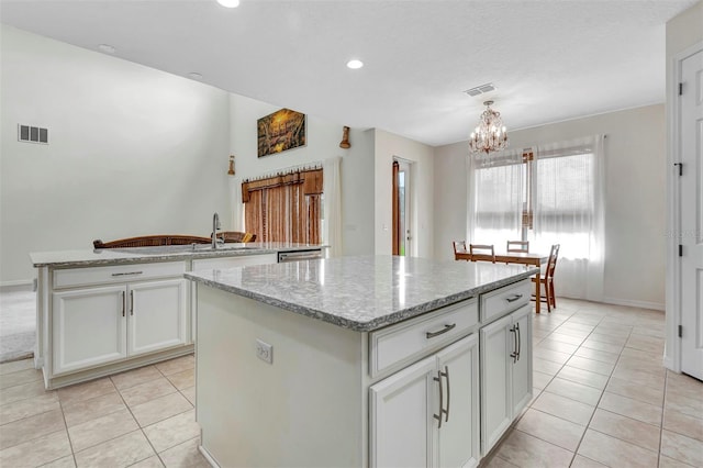 kitchen featuring light tile patterned floors, an inviting chandelier, visible vents, and a center island