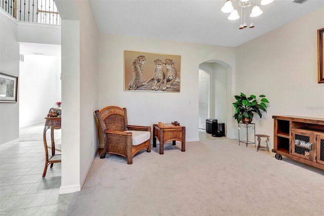 sitting room featuring arched walkways, tile patterned flooring, carpet flooring, visible vents, and baseboards