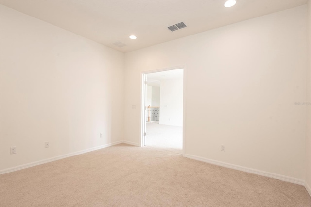 empty room with light colored carpet, visible vents, baseboards, and recessed lighting