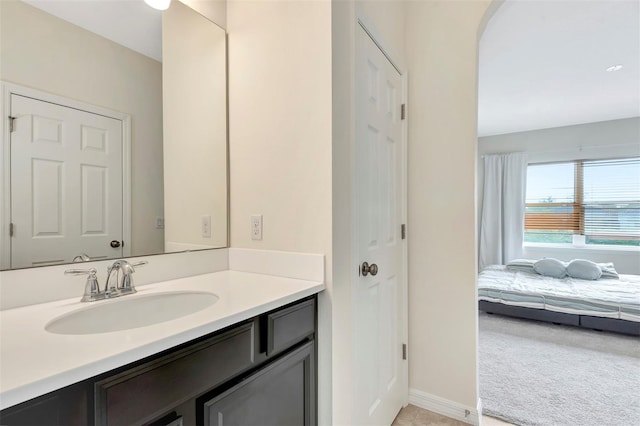 ensuite bathroom with a closet, ensuite bath, vanity, and baseboards