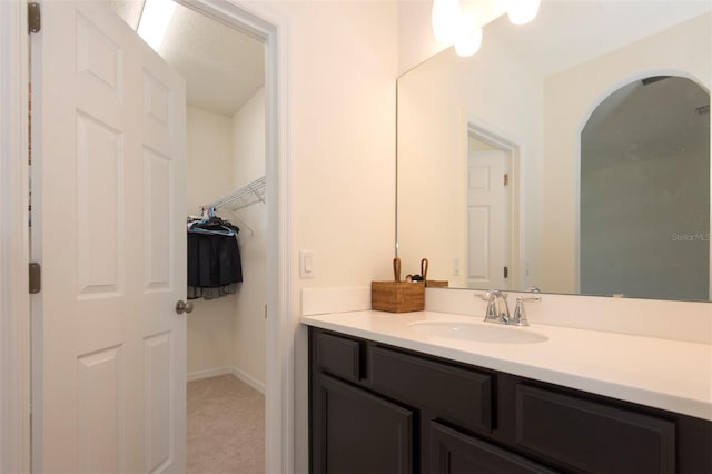 bathroom with vanity, baseboards, and a spacious closet