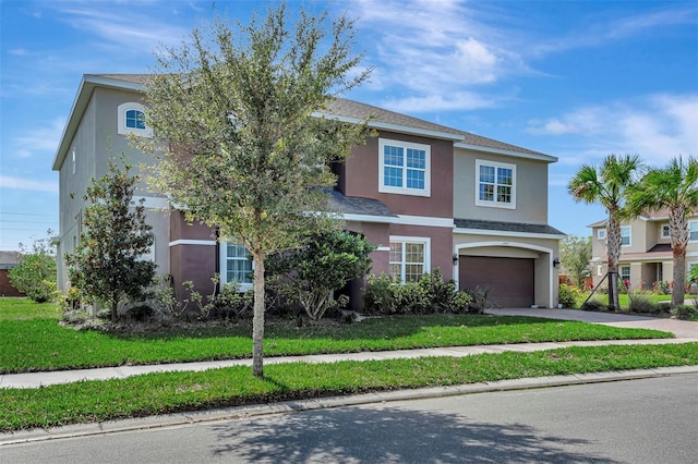 traditional home with a garage, a front lawn, concrete driveway, and stucco siding