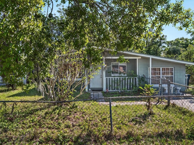 view of property hidden behind natural elements with concrete block siding, fence private yard, and a front lawn