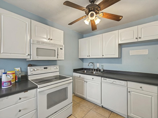 kitchen featuring white appliances, dark countertops, and a sink