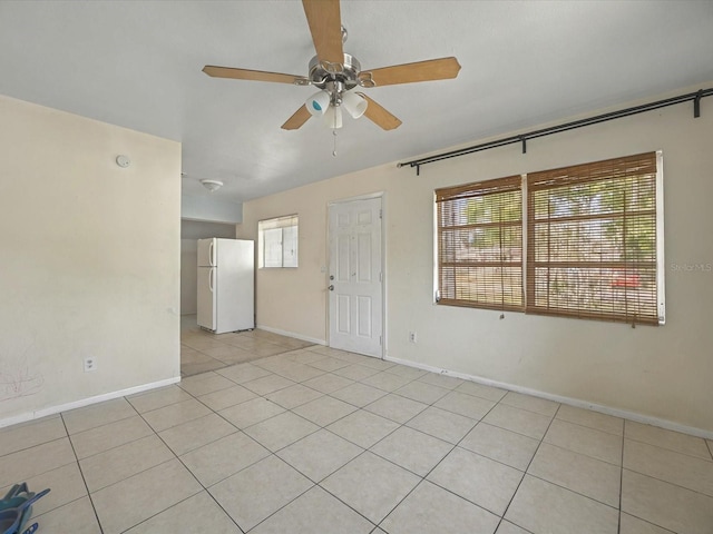 empty room with light tile patterned floors, baseboards, and ceiling fan