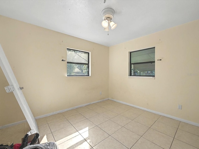 empty room featuring light tile patterned floors, baseboards, and a ceiling fan