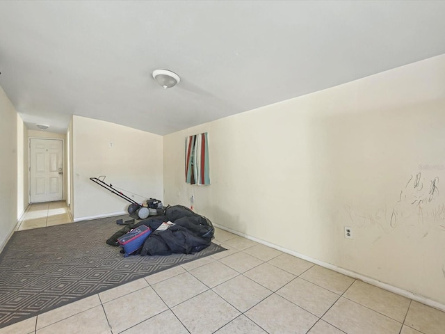 exercise room featuring light tile patterned floors and baseboards