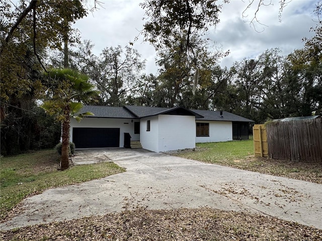 ranch-style house with a garage, fence, driveway, stucco siding, and a front yard