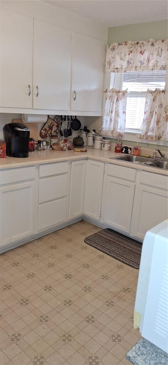 kitchen featuring light countertops, white cabinetry, and a sink