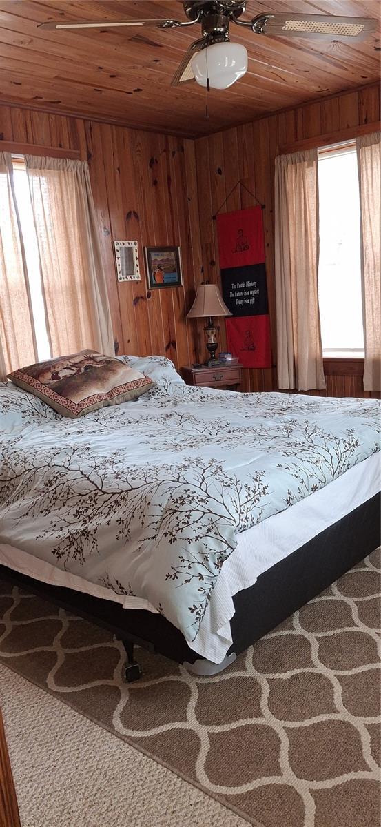 bedroom featuring wood ceiling and wooden walls