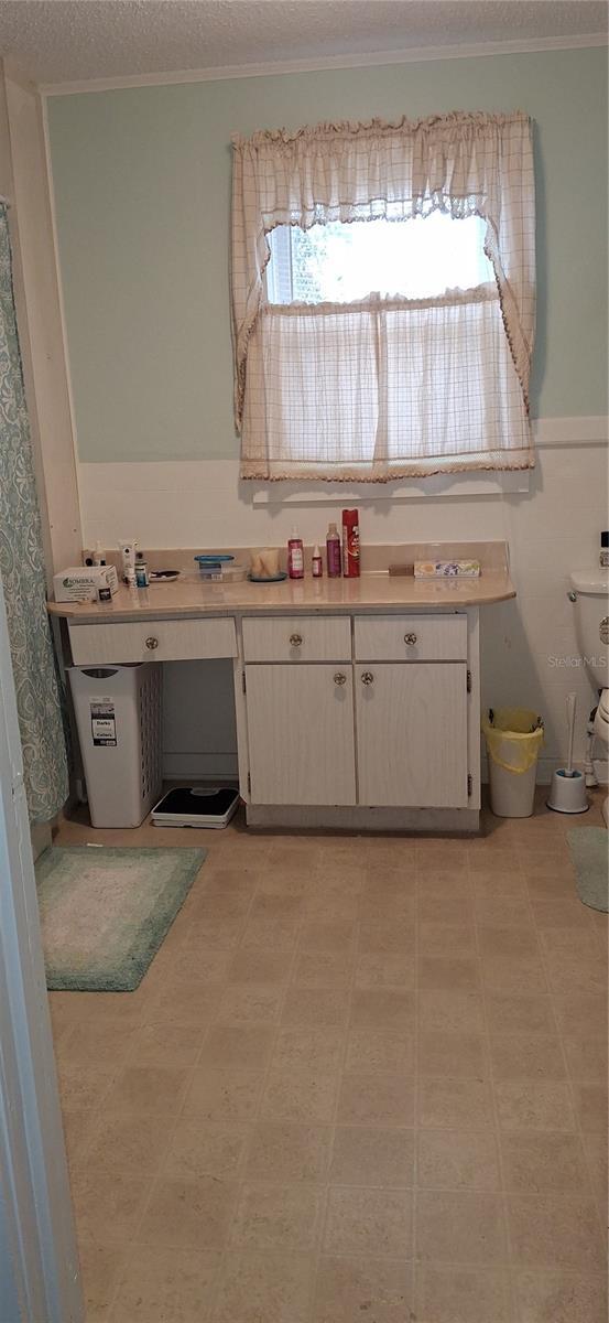 bathroom with crown molding, a textured ceiling, toilet, and tile patterned floors