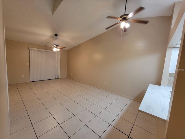 empty room featuring light tile patterned floors, vaulted ceiling, and ceiling fan